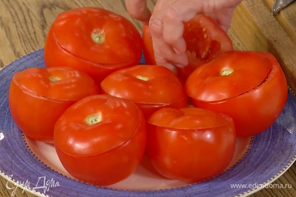 С помидоров срезать верхушки, так чтобы получились крышечки, затем ложкой вынуть всю мякоть и откинуть ее на сито.