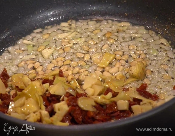 Разогреть в сковороде 2 ст. ложки растительного масла и на небольшом огне обжарить лук и чеснок, затем всыпать тмин и кориандр, добавить кедровые орехи, вяленые помидоры, артишоки, оливки и, помешивая, все обжарить.