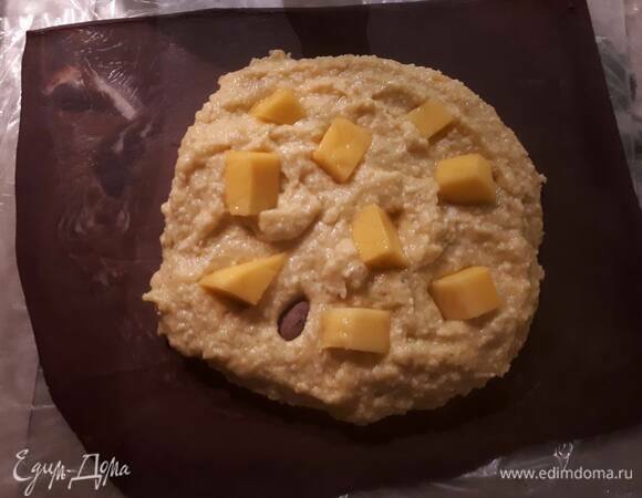 В центр одного квадрата выложите начинку и кусочки манго, оставив примерно 2 см до края. Слегка смочите водой поверхность теста вокруг начинки.