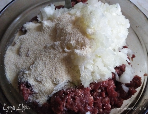 Лук измельчить, соединить с фаршем. Всыпать манку. Перемешать.