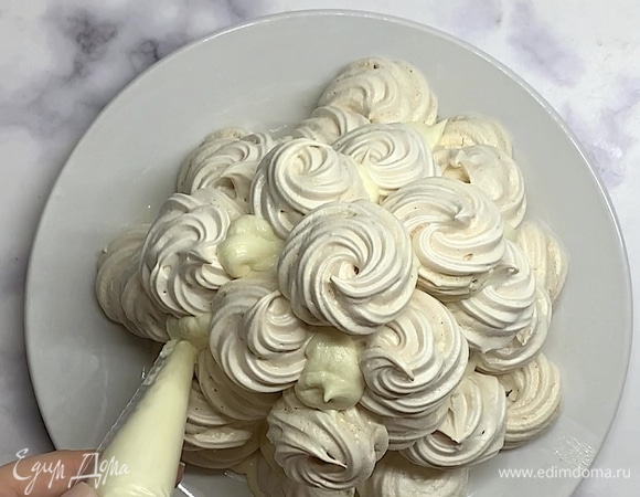 Затем смазываем все безе снизу и выкладываем торт в форме горки. Оставшийся крем отсаживаем в пустые места.