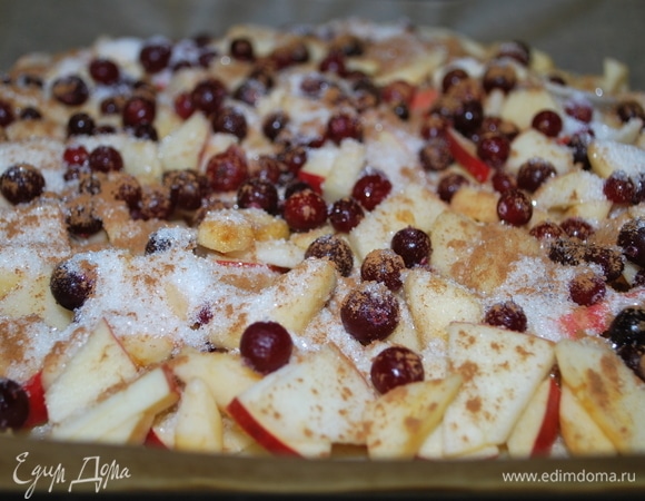 Тесто разделите на 2 части. Одну раскатайте в тонкий пласт, сверху распределите яблоки, разложите ягоды брусники, посыпьте сахаром и корицей.