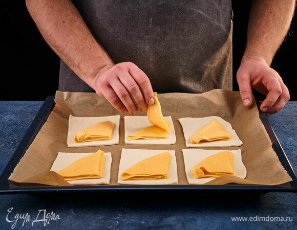 На каждый квадрат выложите по 2 ломтика плавленого сыра, сложенных пополам.