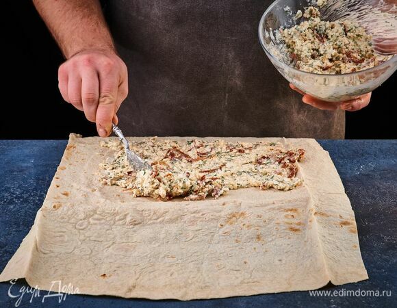 На столе распрямите лист лаваша. Нанесите тонким слоем творожную массу с зеленью.