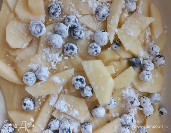 Форму для запекания желательно смазать маслом. Выкладываем половину теста. На него раскладываем яблоко и чернику.