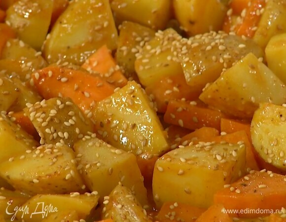 Снять фольгу, полить картофель заправкой, посыпать кунжутом и запекать еще 10 минут.