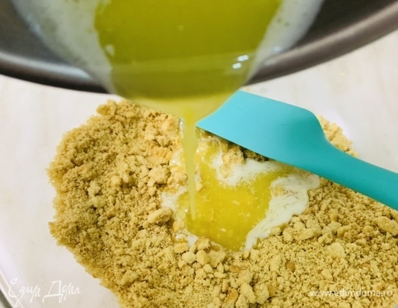 Измельчить печенье в мелкую крошку. Залить растопленным сливочным маслом. Перемешать до однородности.