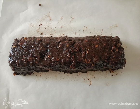 Соединить печенье и шоколад. Перемешать. Выложить массу на лист пергаментной бумаги и придать форму салями.