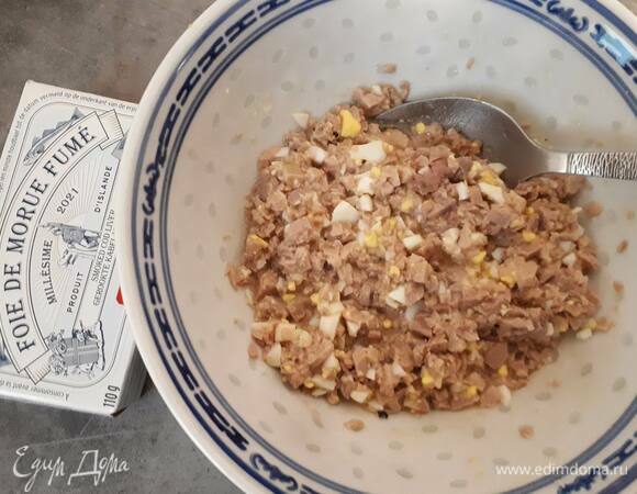 Откройте банки с печенью трески. Печень выньте из масла и нарежьте очень мелко. Смешайте с яйцом и добавьте 1–2 ст. л. масла из банки. Посолите, поперчите и хорошо перемешайте.