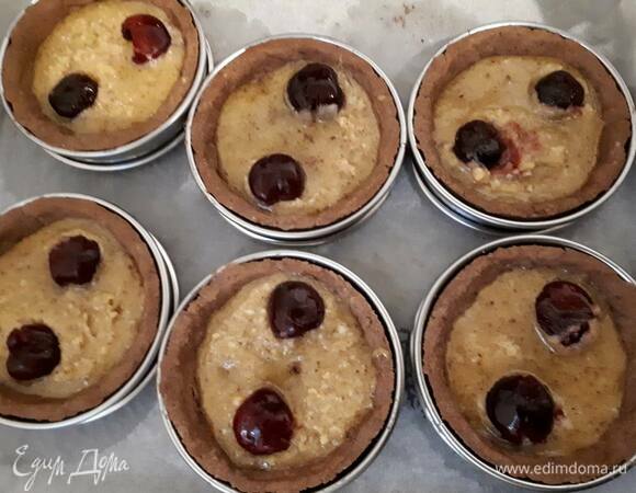 Затем выложите крем в тарталетки и добавьте по 2 вишни. Вишни нужно слегка утопить в креме. Поставьте в духовку еще на 12 минут.