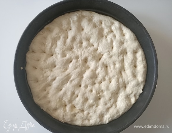 Форму диаметром 28 см щедро смазать оливковым маслом. Выложить тесто и распределить его, делая пальцами небольшие вмятины.