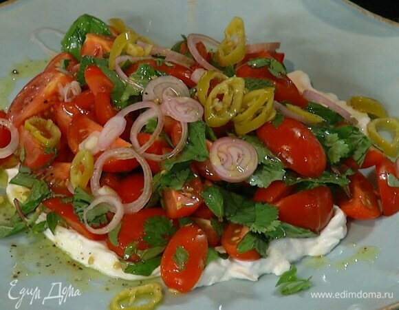 Нарезанные помидоры соединить с измельченной зеленью, посолить, поперчить и перемешать, затем выложить на подушку из козьего сыра, посыпать замаринованным луком и полить заправкой.