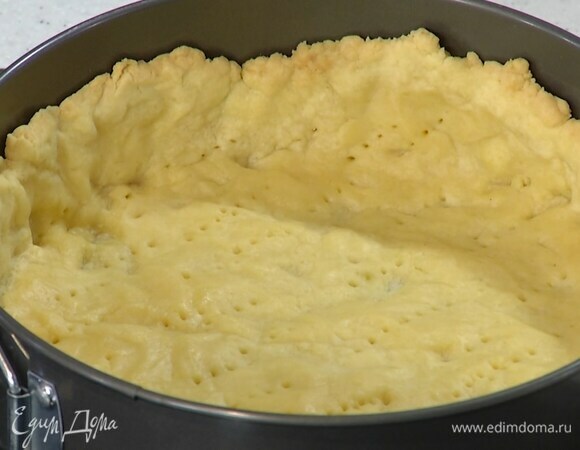 Выстелить дно разъемной формы бумагой для выпечки, выложить половину теста и сформировать корж с высокими бортами, часто наколоть его вилкой, накрыть бумагой, всыпать любые бобовые и выпекать в разогретой духовке 15 минут.