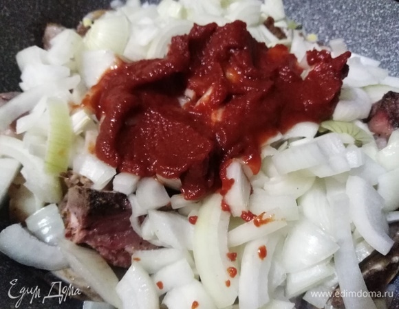 На ребра выложить репчатый лук и томатную пасту. Убавить огонь до минимума. Накрыть крышкой и томить в течение 1 часа.