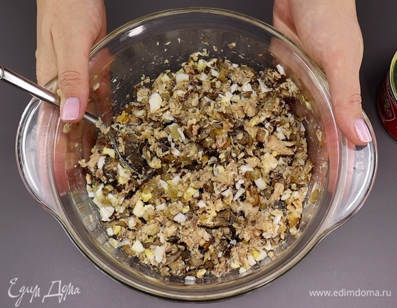 Далее два вареных яйца нарезаем кубиком и добавляем к рыбе. Сюда же отправляем и полностью остывшие жареные грибы с луком. Перемешиваем — начинка для пирога готова. Я буду выпекать пирог в форме диаметром 20 см, можно взять и большего диаметра, но учитывайте, что пирог получится ниже. Дно металлической формы застилаем бумагой для выпечки и переливаем половину теста. Если форма стеклянная или силиконовая, просто смажьте растительным маслом.