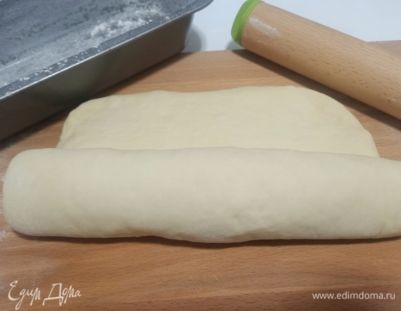 Поднявшееся тесто выложить на посыпанный мукой стол. Раскатать скалкой в прямоугольник толщиной около 2 см, затем свернуть рулетом.