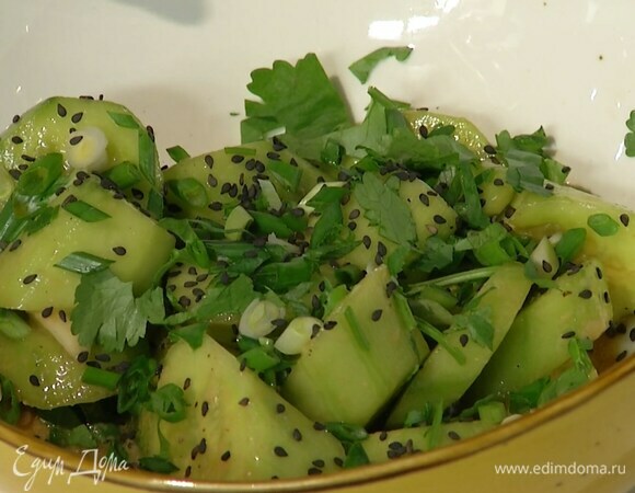 В глубокую салатницу всыпать половину нарезанного зеленого лука и кинзы, затем выложить огурцы вместе с заправкой, посыпать оставшейся зеленью и кунжутом.