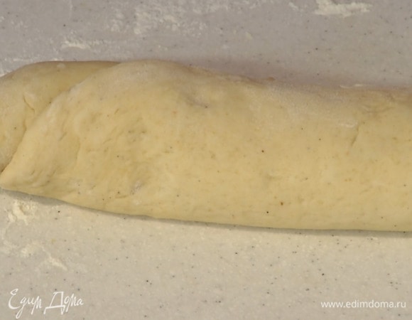 Подошедшее тесто выложить на присыпанную оставшейся мукой рабочую поверхность и раскатать в прямоугольный пласт толщиной 3–5 мм, затем смазать начинкой, свернуть по длинной стороне в рулет.