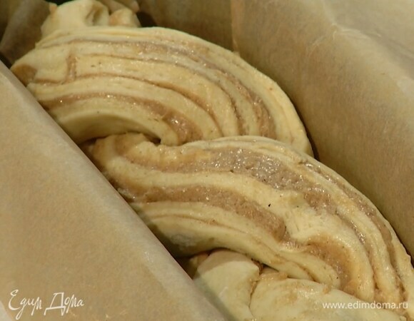 Немного отступив от одного края, разрезать рулет вдоль и сплести в косичку, затем выложить в прямоугольную форму для кекса, выстеленную бумагой для выпечки, накрыть влажным полотенцем и оставить в теплом месте на 15–20 минут.