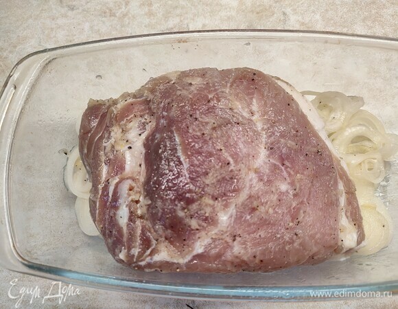 Духовку разогреть до 220°C. Развернуть мясо из пленки. На дно формы, в которой будет запекаться мясо, выложить весь лук, а сверху положить свинину. Запекать 15 минут. Потом уменьшить температуру до 200°C и запекать еще 35 минут.