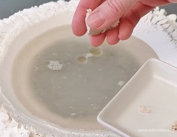 В углубление влить воду, растительное масло. Затем, измельчая руками, вводим свежие дрожжи. Перемешиваем вилкой до однородности. Затем, двигаясь от центра углубления к краям, постепенно смешиваем муку и жидкую массу. Все ингредиенты объединятся. Переходим к замешиванию.