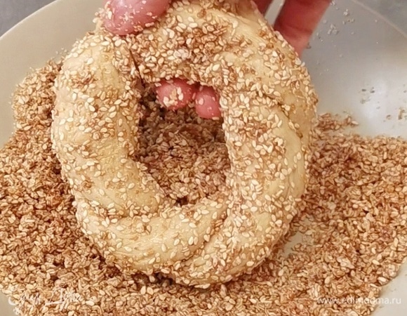 После обваляйте в кунжуте, следите за тем, чтобы семена полностью покрыли поверхность и бока бублика. Выложите бублики на противень с пергаментом, накройте пленкой и полотенцем, оставьте на 20 минут.