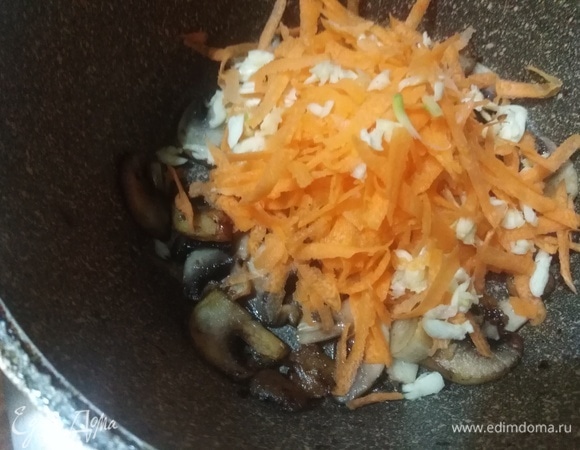 Добавить натертые на крупной терке морковь и чеснок. Жарить 2–3 минуты.