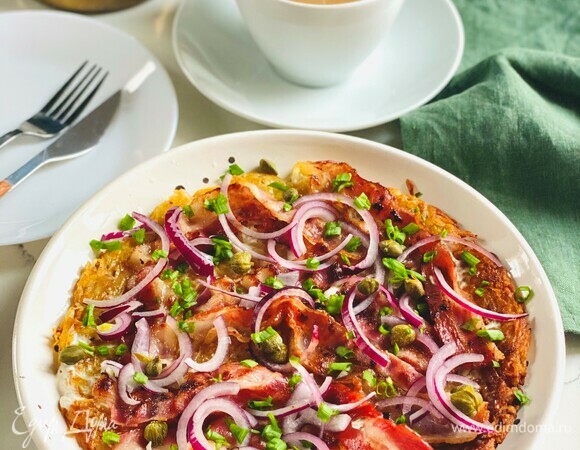 Лепешку выложить на большую тарелку, смазать сметаной, разложить по всей поверхности бекон и лук, посыпать каперсами и зеленью.