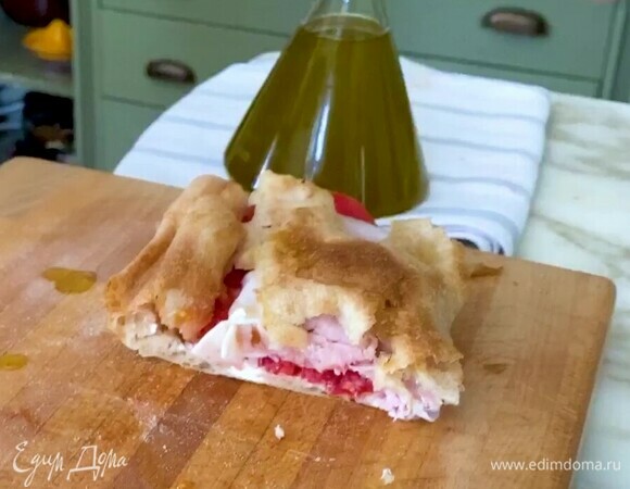 Верхнюю половину лепешки сбрызнуть оливковым маслом, накрыть начинку и разрезать панино на части.