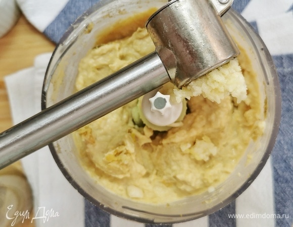 После добавляем измельченный чеснок, тахиновую пасту, свежемолотый черный перец, перец красный и молотый кумин (зиру). Понемногу вливаем воду. Измельчаем блендером, добиваясь консистенции пюре, в котором не должно остаться крупинок.