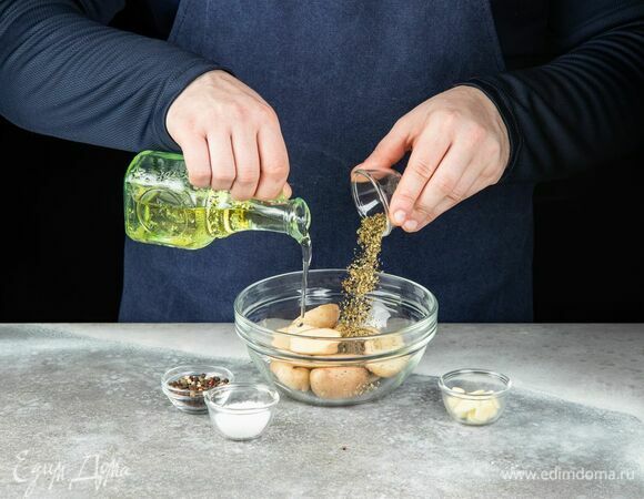 В глубокую чашу выложите разрезанный на половинки картофель, полейте оливковым маслом, добавьте рубленый чеснок, орегано, тимьян, соль и перец.<br />
Запекайте в разогретой до 180°C духовке около 20 минут.