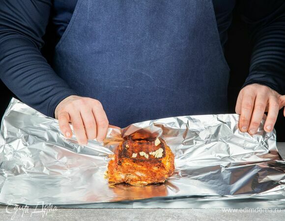 Заверните мясо в фольгу, полейте оливковым маслом и обложите рубленым чесноком. Запекайте в разогретой до 200°С духовке 1 час.
