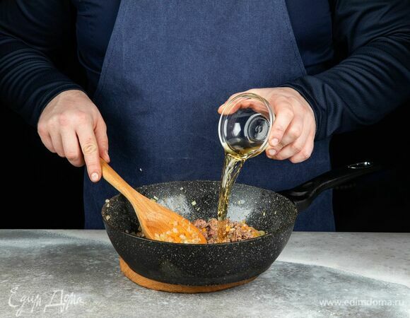 Влейте белое вино. Перемешайте и тушите до выпаривания алкоголя.