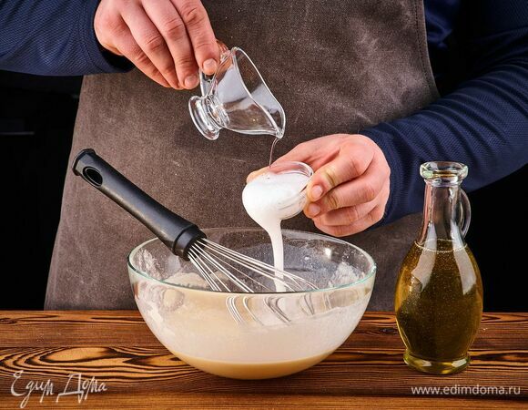 В отдельной миске погасите соду уксусом. Добавьте в тесто, перемешайте.<br />
Влейте растительное масло, перемешайте. Должно получиться жидкое тесто. <br />
Накройте чашу с тестом полотенцем и оставьте на 15–20 минут при комнатной температуре.