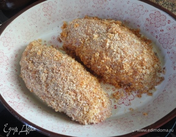 Для панировки смешайте сухари с гранулированным чесноком и солью. Я еще добавила свежемолотый черный перец и немного красной сладкой паприки. В плоскую посуду разбейте яйцо и слегка взбейте вилкой. Обмакнуть грудки сначала в яйце, затем — в сухарях. Снова обмакнуть в яйце и последний раз в сухарях. Выложить в форму для запекания, смазанную растительным маслом. Я от себя добавила в форму 2 ст. л. воды.