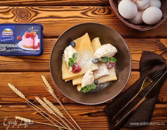 Готовые блины сложите треугольником, выложите банановый крем-чиз, украсьте ягодами, листочками мяты и посыпьте сверху сахарной пудрой.