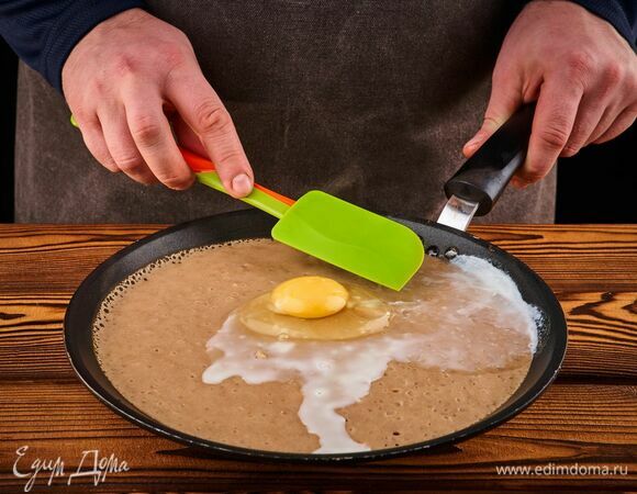 Разогрейте сковороду на среднем огне. С помощью половника выложите на сковороду тесто. Как только на нем появятся пузырьки, разбейте в центр яйцо. С помощью лопатки распределите белок по всей поверхности блина, но желток оставьте нетронутым.