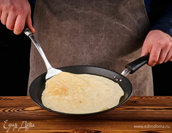 Хорошо разогрейте сковороду. Зачерпните половником тесто, влейте на сковороду и быстро распределите по всей поверхности. Когда тесто схватится, а края начнут темнеть, переверните блин на другую сторону. Пожарьте так остальные блины.