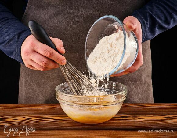 Всыпьте просеянную муку. Добавьте небольшое количество воды, перемешайте венчиком до однородности.