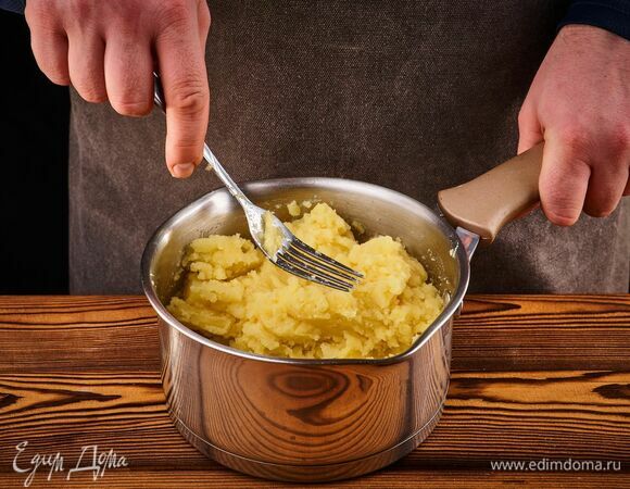 Тем временем картофель почистите и отварите до готовности. Разомните толкушкой в пюре.