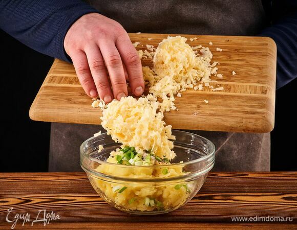 К пюрированному картофелю добавьте сметану, тертый сыр, мелко нарезанный зеленый лук, соль и перец. Перемешайте.