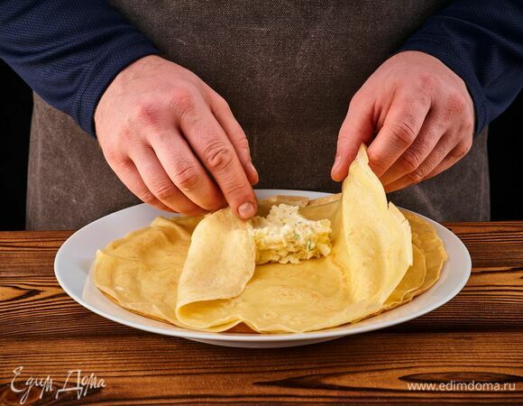 В центр каждого блина положите 2–3 ст. л. начинки, заверните конвертом.