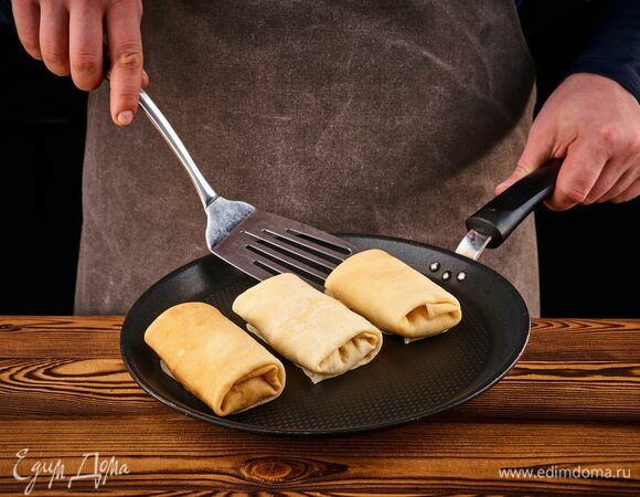 На готовые блины выложите начинку, сверните конвертиками и чуть обжарьте на растительном масле с обеих сторон.