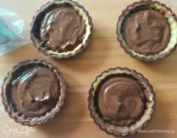 Из холодильника достать формочки с тестом. Выложить шоколадный заварной крем, не доходя до края 0,5–0,7 см.
