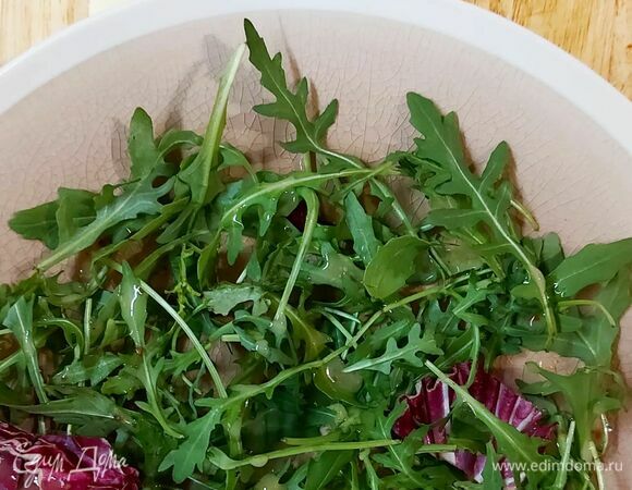 Выложите на блюдо руколу. Немного полейте ее заготовленным соусом. Выложите нарезанные черри, бекон, сельдерей, халуми. Полейте салат остатками соуса.