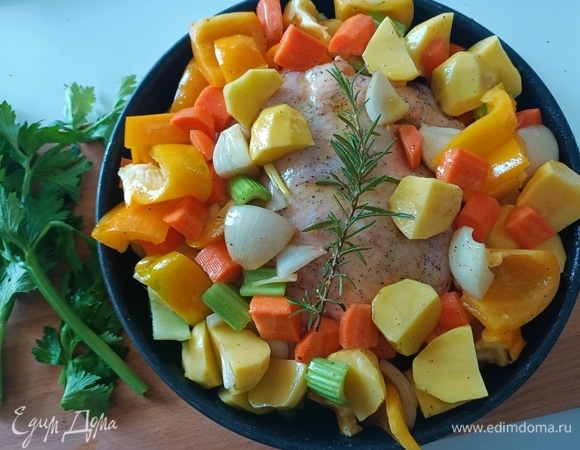 В форму уложить курицу, полить оливковым маслом. Затем выложить овощи. Отправить в предварительно разогретую до 180°С духовку.