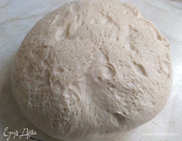 Готовое тесто выложите на стол. Для этого емкость, в которой бродило тесто, переверните вверх дном — тесто само упадет на стол.