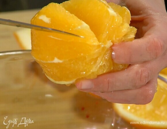 С апельсина срезать корки и над миской с салатом вырезать из перепонок мякоть.