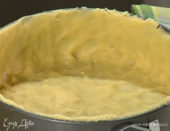 Дно разъемной формы выстелить бумагой для выпечки, выложить тесто и сформировать тонкий корж с высокими бортиками.