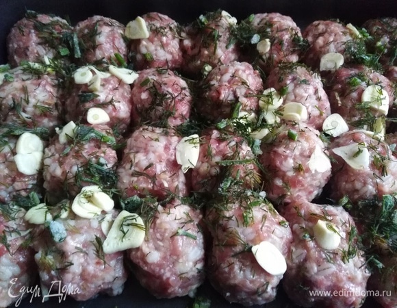 Сформировать тефтели. Выложить в форму для запекания. Посыпать нарезанным чесноком и зеленью.